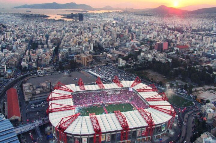 Aerial view of Georgios Karaiskakis Stadium in Piraeus at sunset, full crowd before Olympiacos vs Real Madrid.