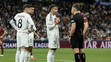 Referee talks with three Real Madrid players during a tense moment.