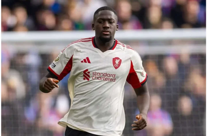 Ibrahima Konate Real Madrid- Liverpool defender in a white and red away kit running during a match, with the crowd blurred in the background.