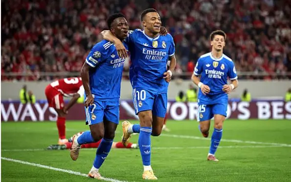 Two Real Madrid players in blue away kit celebrate a goal together during a Champions League match away to Olympiacos.