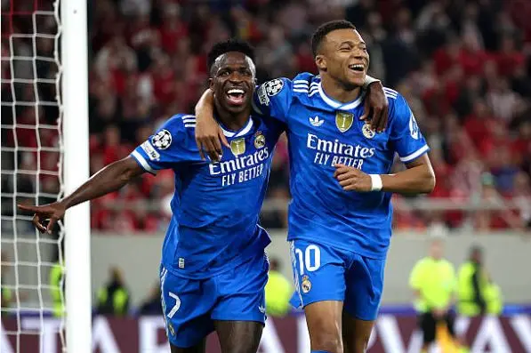 Olympiacos vs Real Madrid analysis – Real Madrid’s 4-2-3-1 shape on the tactical board -Vinícius Júnior, Kylian Mbappéin blue away kit celebrate a goal together, smiling and running with an arm around each other during a Champions League match. 