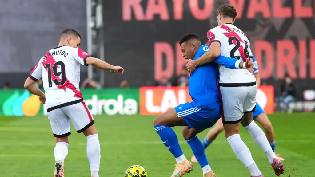 Kylian Mbappé holds off two Rayo Vallecano defenders in LaLiga.