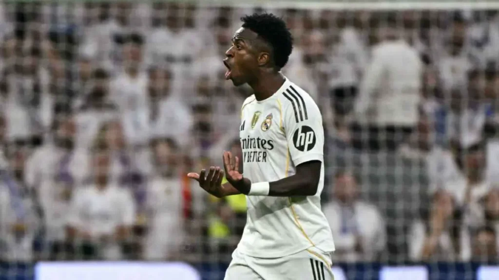 Vinícius Jr and Real Madrid star reacting passionately during a match, gesturing with his hands in front of the home crowd.