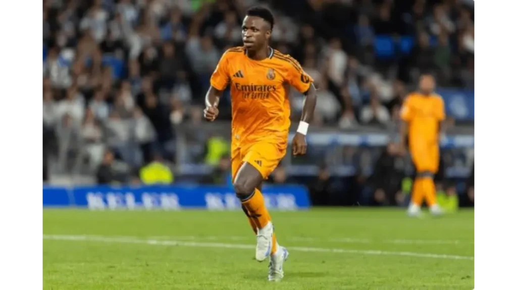 Vinícius Jr contract renewal -Vinícius Jr and Real Madrid winger in the orange away kit sprinting with the ball during a La Liga match.