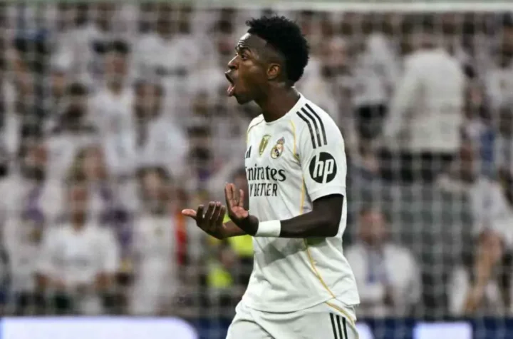 Vinícius Jr and Real Madrid star reacting passionately during a match, gesturing with his hands in front of the home crowd.