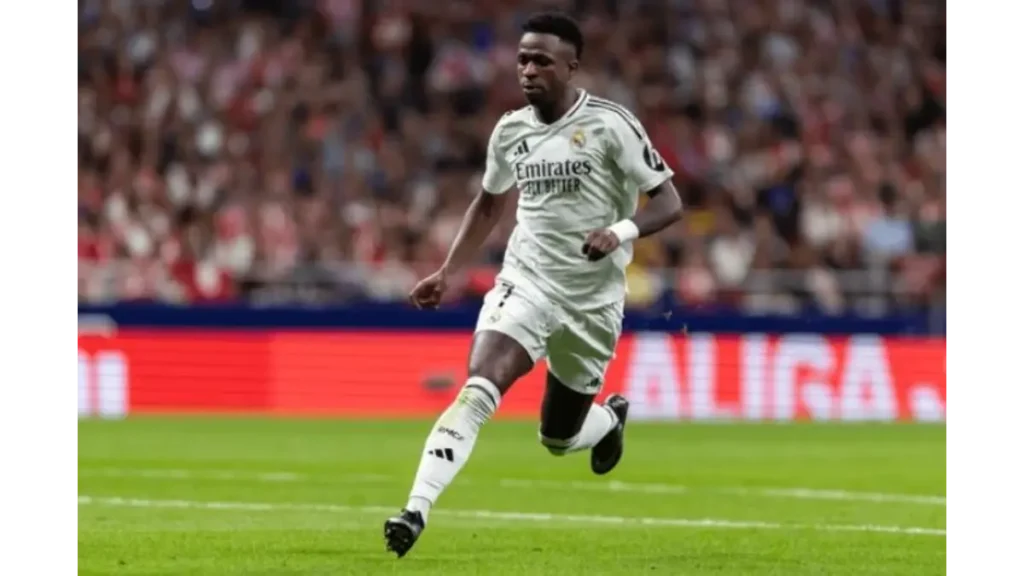 Vinícius Jr and Real Madrid forward in the white home kit sprinting down the flank with the crowd blurred in the background.
