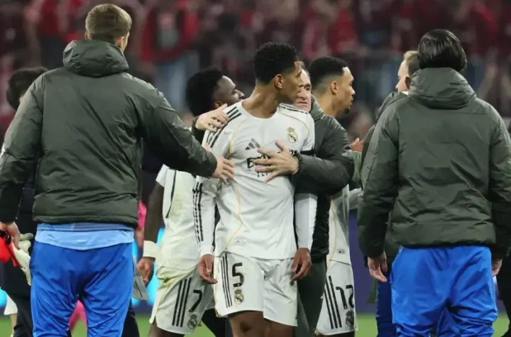 Jude Bellingham is held back by Real Madrid staff and teammates during a tense post-match scene.