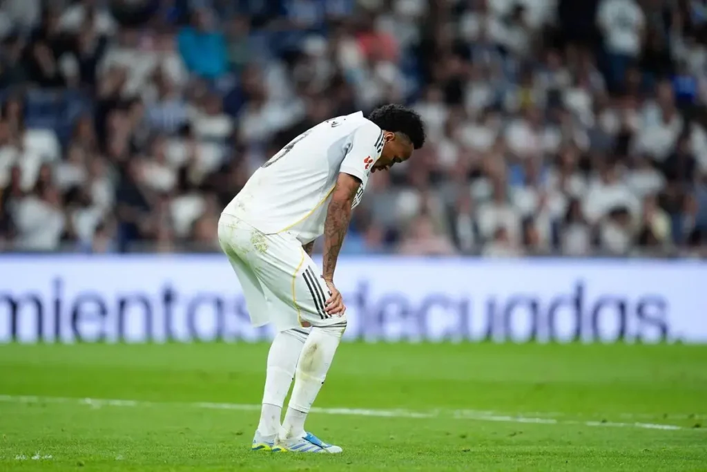 Real Madrid defender bends over in discomfort during a match after suffering a leg injury.