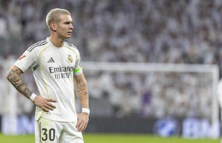 A Real Madrid player stands with his hands on his hips during a match, looking frustrated.