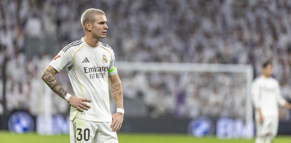 A Real Madrid player stands with his hands on his hips during a match, looking frustrated.