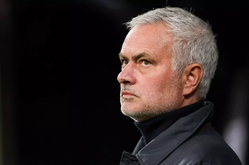 Close-up of a football manager watching from the sideline during a match.