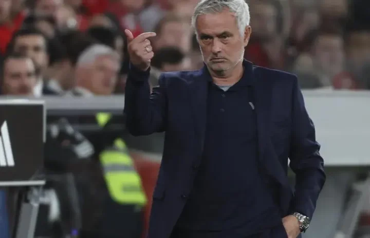 Football manager gesturing on the touchline during a match.