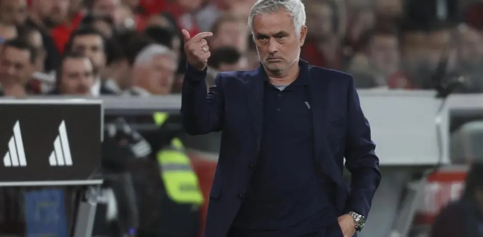Football manager gesturing on the touchline during a match.