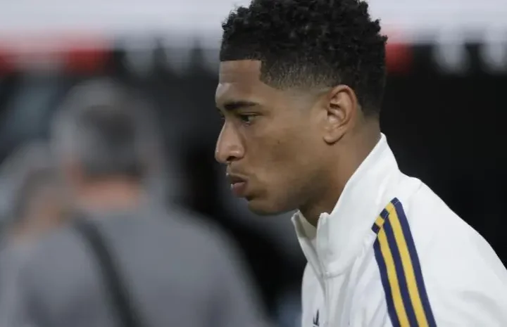 Real Madrid player in a white training jacket shown in side profile before a match
