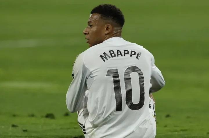 A Real Madrid player in a white No. 10 shirt sits on the field and looks over his shoulder during a match.