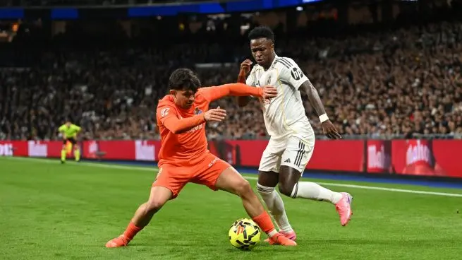 Real Madrid player challenges an opponent in orange for the ball near the sideline during a match.
