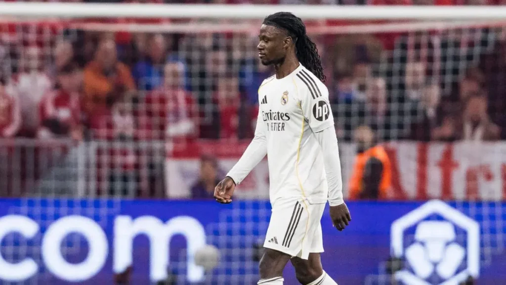 Real Madrid player walking on the pitch during a match with the goal net in the background.