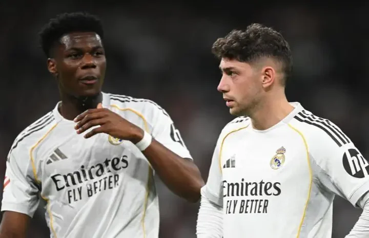 Two Real Madrid players in white kits stand together during a match, with one gesturing as they talk on the pitch-Aurelien Tchouameni Manchester United