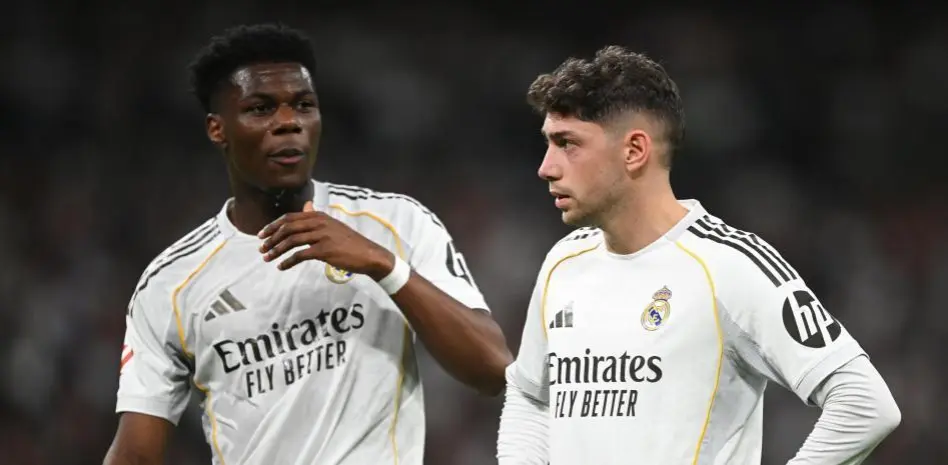 Two Real Madrid players in white kits stand together during a match, with one gesturing as they talk on the pitch-Aurelien Tchouameni Manchester United