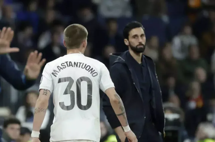 Real Madrid player wearing a shirt with “Mastantuono 30” on the back walks past the coach on the touchline during a match