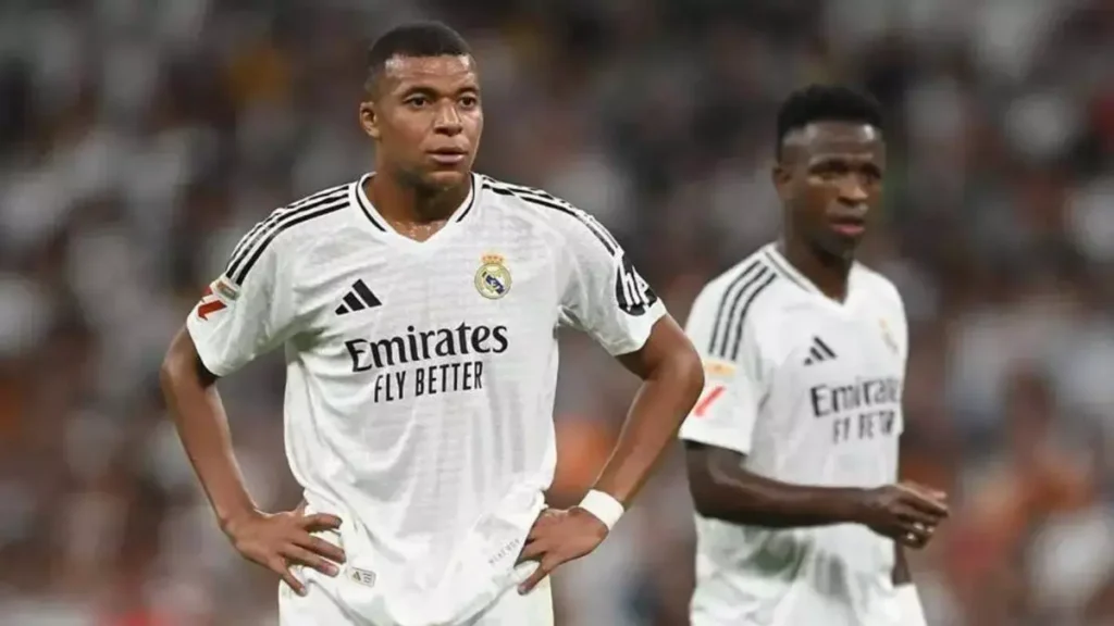 Two Real Madrid players stand on the pitch during a match with serious expressions.