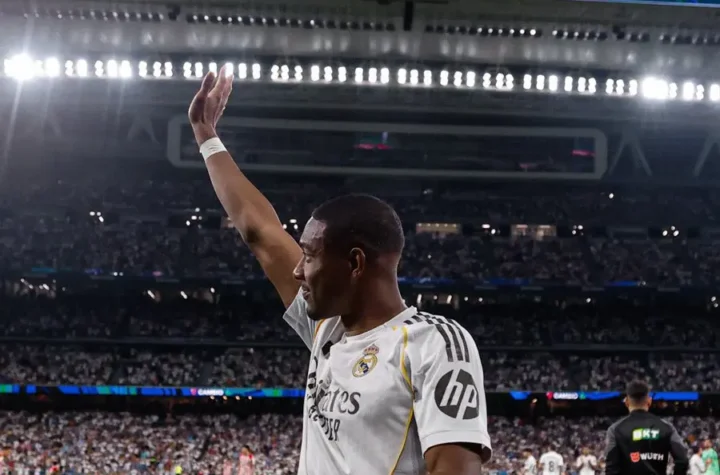 David Alaba waves to fans during his Real Madrid farewell at the Bernabéu as tribute screens display “Gracias, David” and “Danke, David”