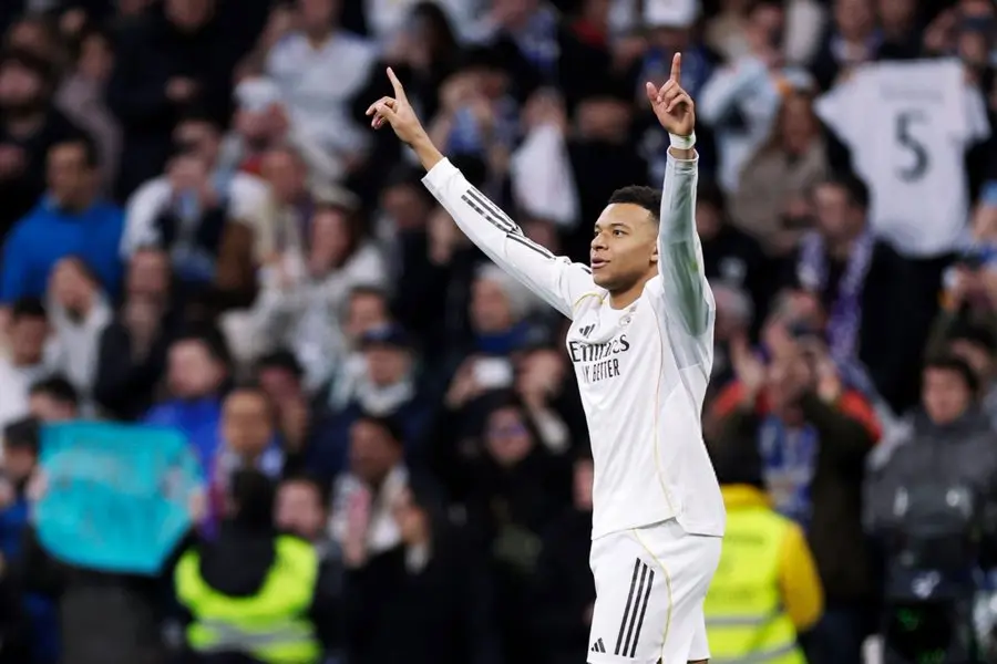 Real Madrid player raises both arms toward the crowd during a match in Kylian Mbappe Real Madrid coverage