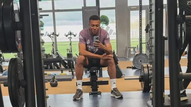 Kylian Mbappe injury update related image showing a footballer seated in the gym during an individual recovery session