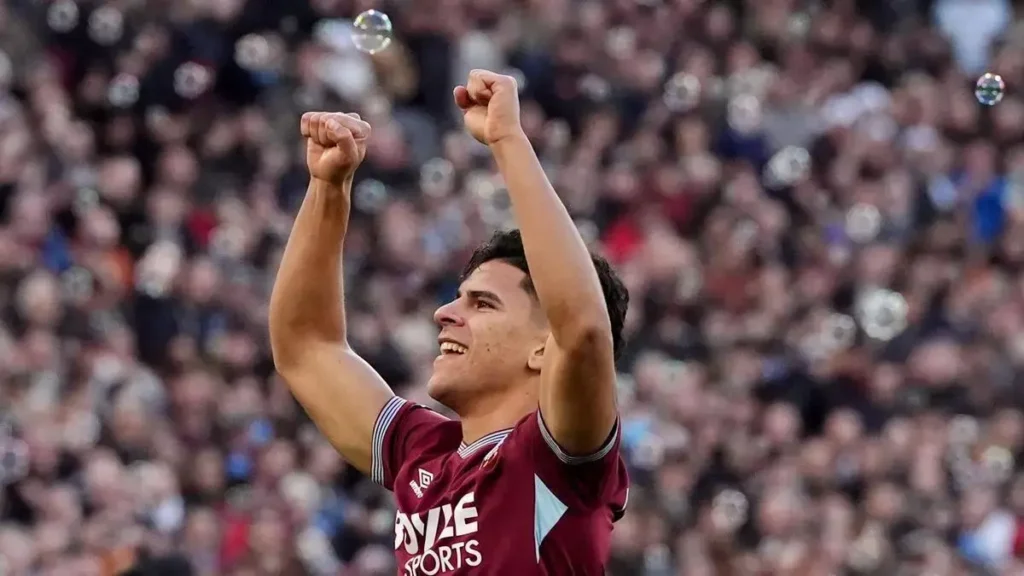Footballer celebrating with both arms raised in front of a crowd