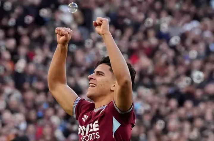 Footballer celebrating with both arms raised in front of a crowd