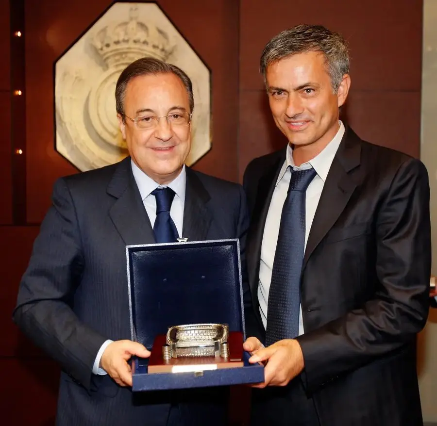 Real Madrid transfer news featured image showing two men in suits holding a presentation piece at a club event