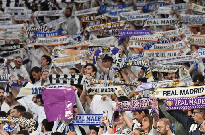 How to become a Real Madrid member featured image showing supporters holding club scarves inside the Santiago Bernabéu