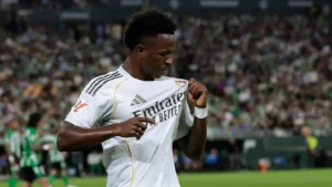 Real Madrid forward holds the club badge during a match, illustrating the emotional Vinicius renewal message.